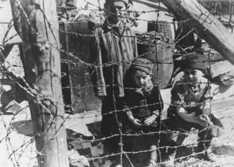 Bambini col pigiama a righe dietro una rete con filo spinato a Buchenwald nella II Guerra Mondiale